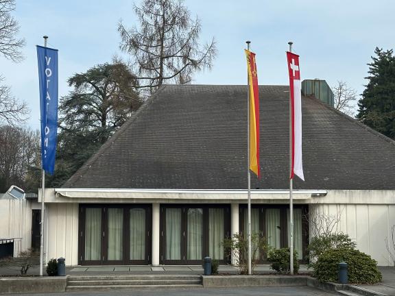 Vue d'une des façade de la Salle communale de Cologny avec les drapeaux pour les votations