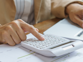 illustration: vue d'une table avec des documents, une calculatrice et la main d'une personne