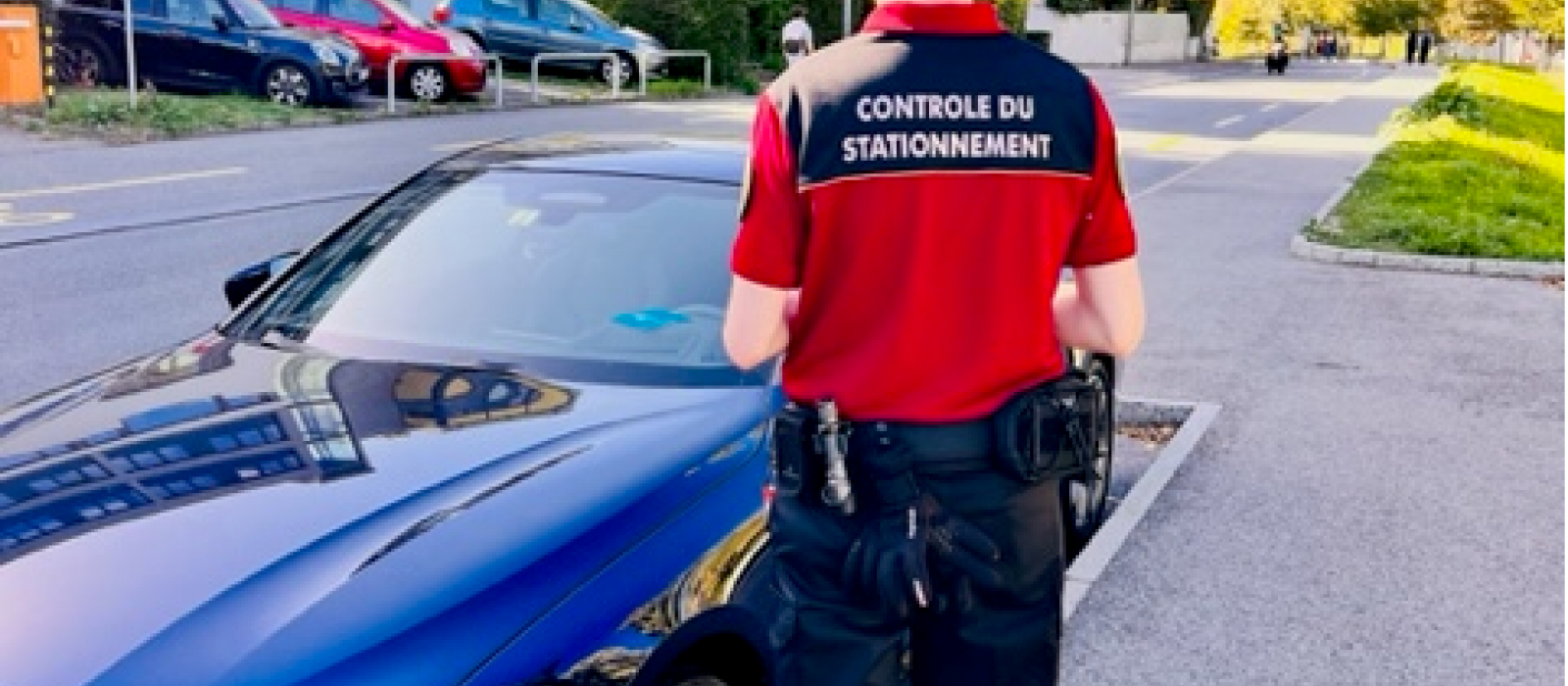 Contrôleur du stationnement de dos vers un véhicule stationné en bord de route