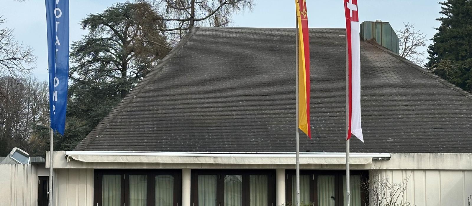 Vue d'une des façade de la Salle communale de Cologny avec les drapeaux pour les votations