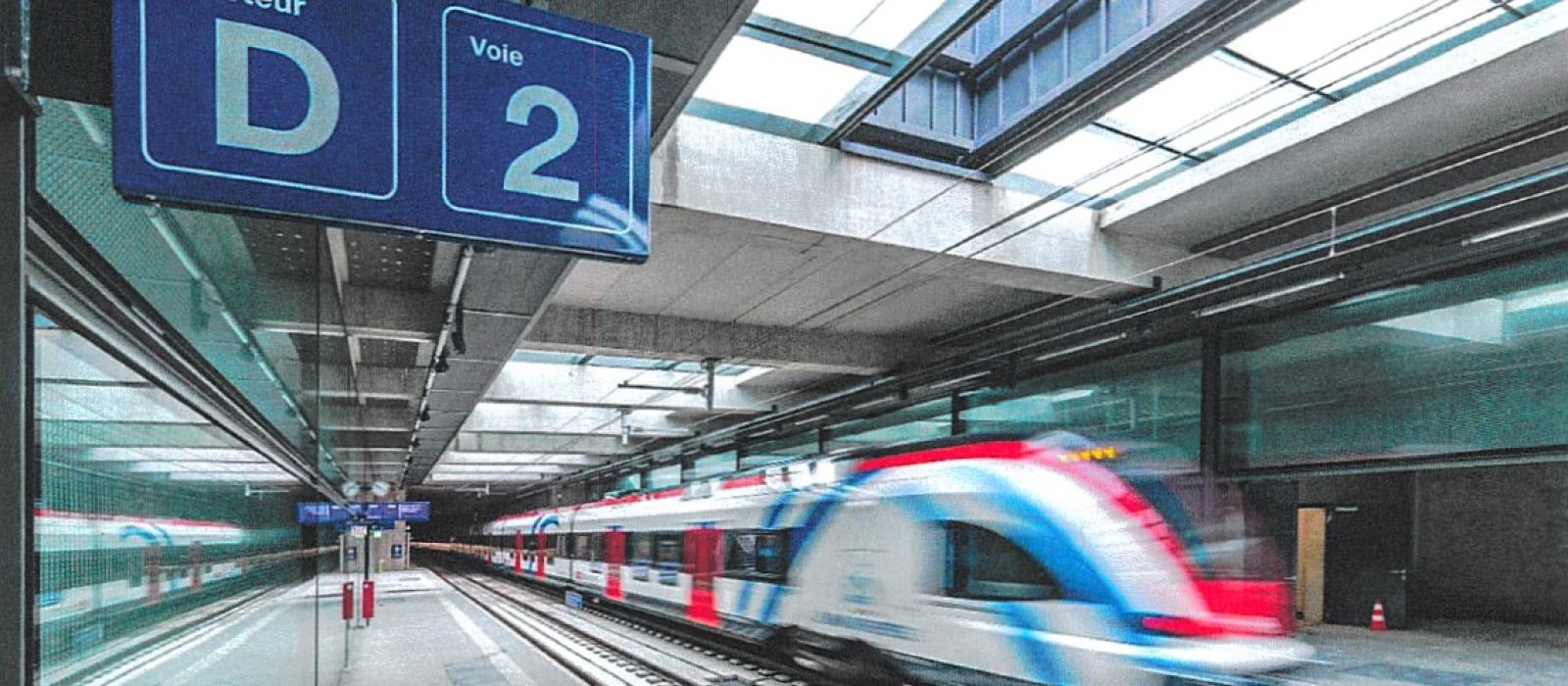 qui d'une gare souterraine du Léman express avec un train en mouvement